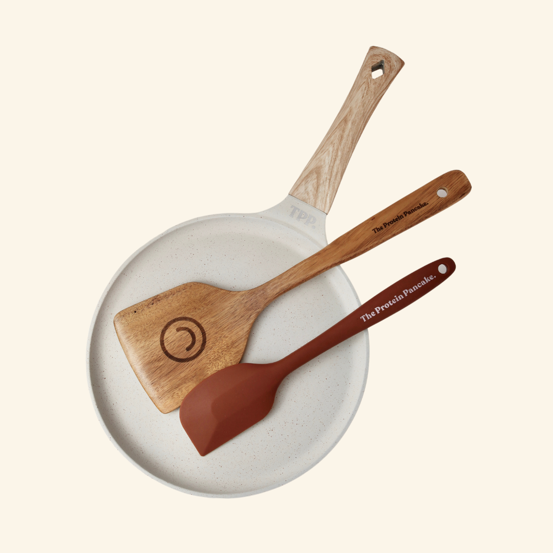 White ceramic pan with two wooden spatulas on a neutral background.