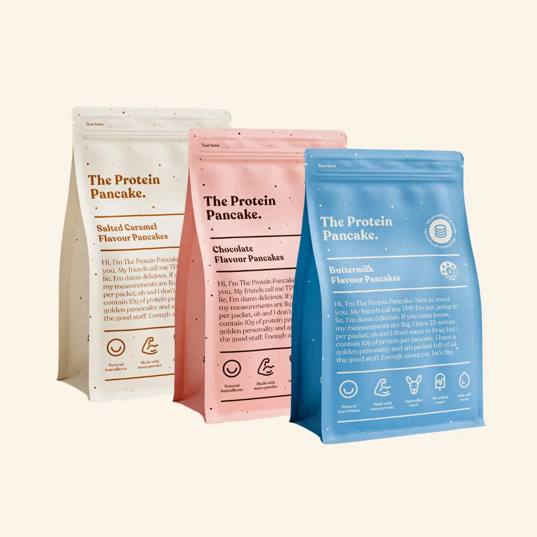 Three colorful packages of The Protein Pancake in various flavors.